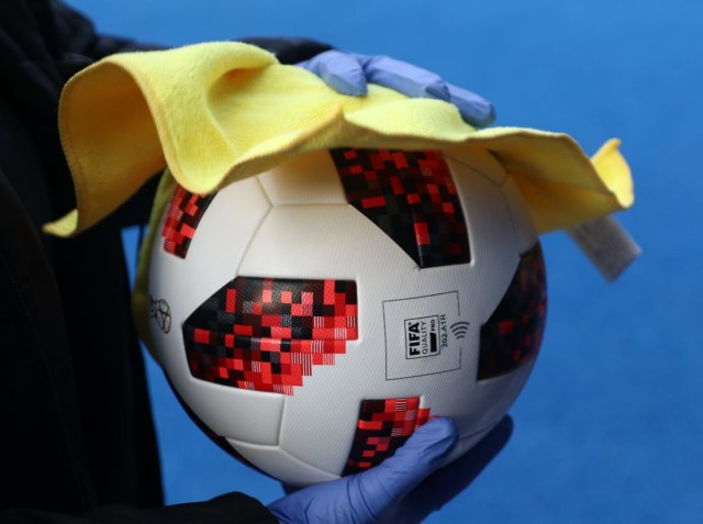 Imagen ilustrativa de la pelota agarrada con guantes, simbolizando la seguridad sanitaria.