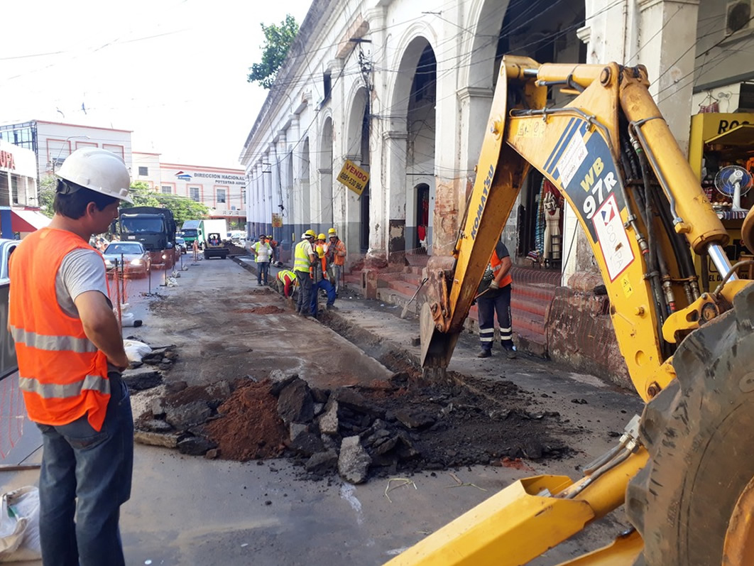 Trabajos de desagüe cloacal sobre la calle Colón de Asunción. Se puede ver una zanja abierta con un tractor de excavación y funcionarios de MOPC.