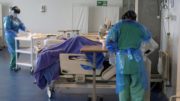 Médicos vistiendo traje de bioseguridad atendiendo a pacientes en el hospital.