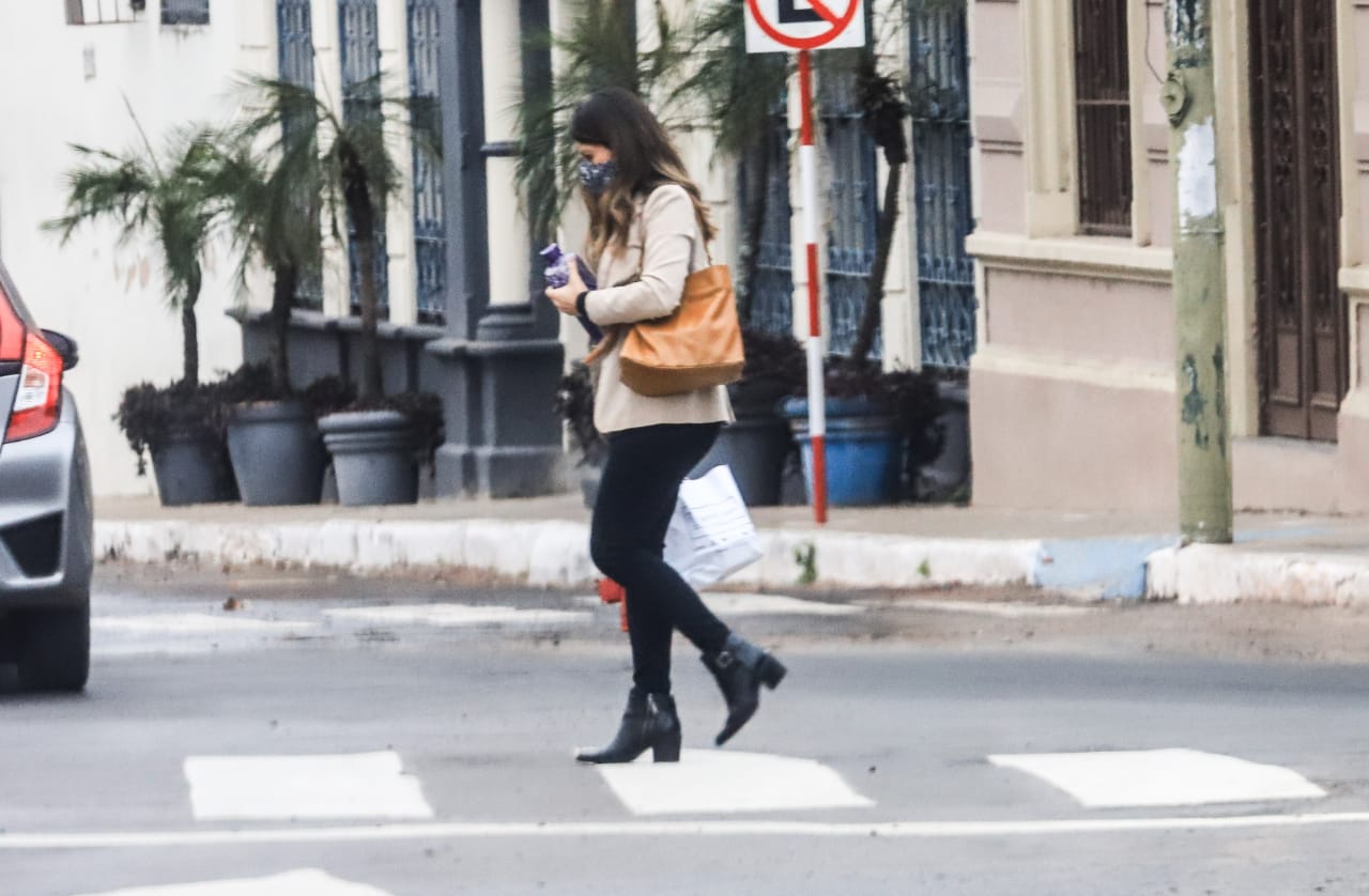 Mujer cruzando la calle con tapabocas.