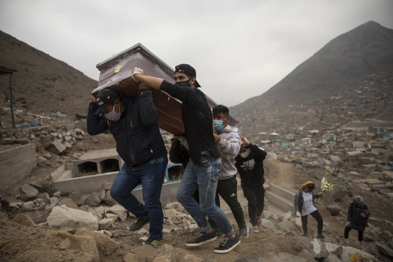 Personas alzando un cajón fúnebre en Perú.