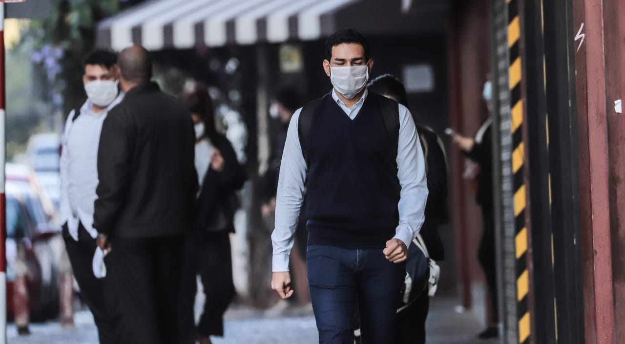 Personas caminando en la calle, con tapabocas.