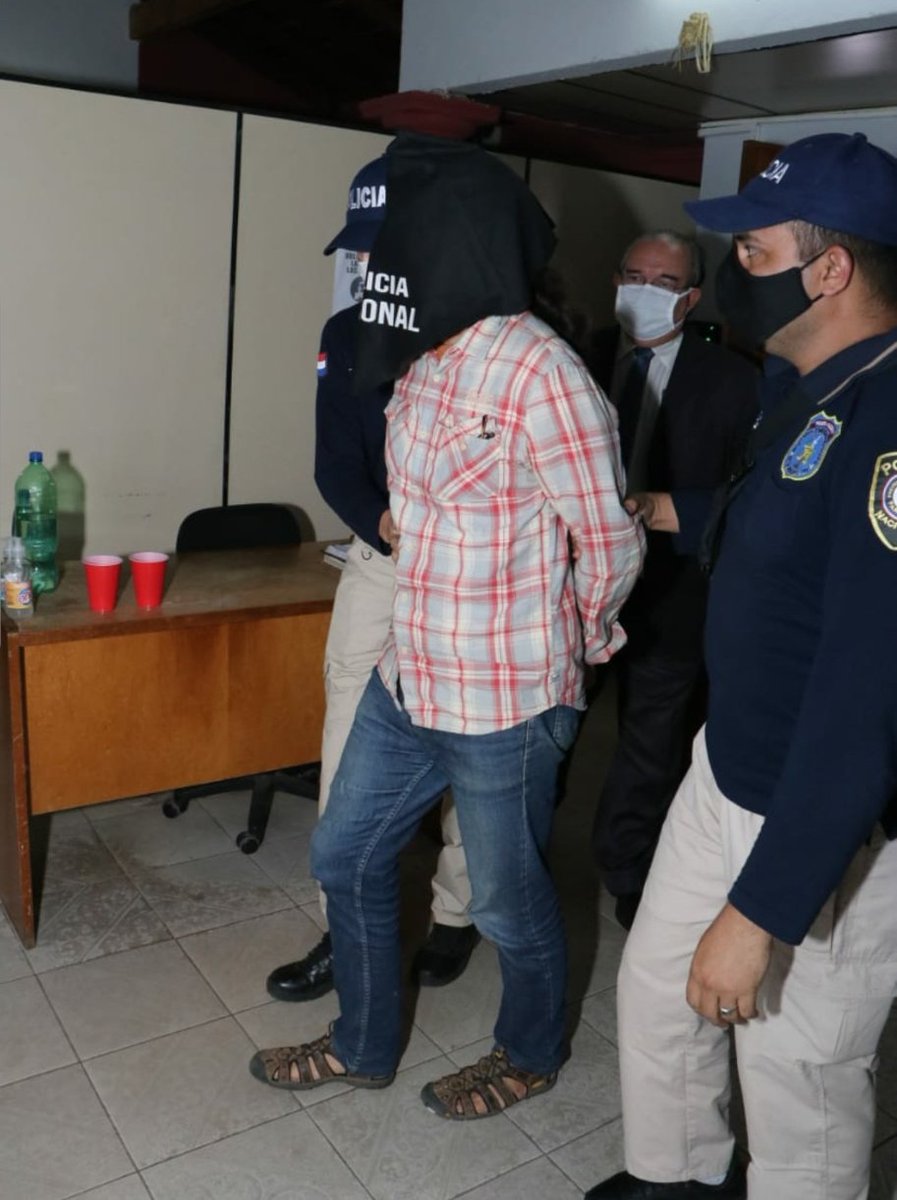 Reiner Oberüber llegando a la fiscalía encapuchado, acompañado de agentes policiales.
