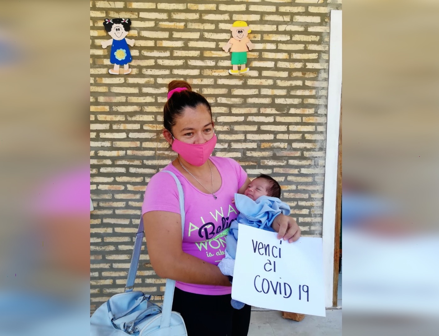 Madre con bebé en brazos y cartel de vencí al covid.