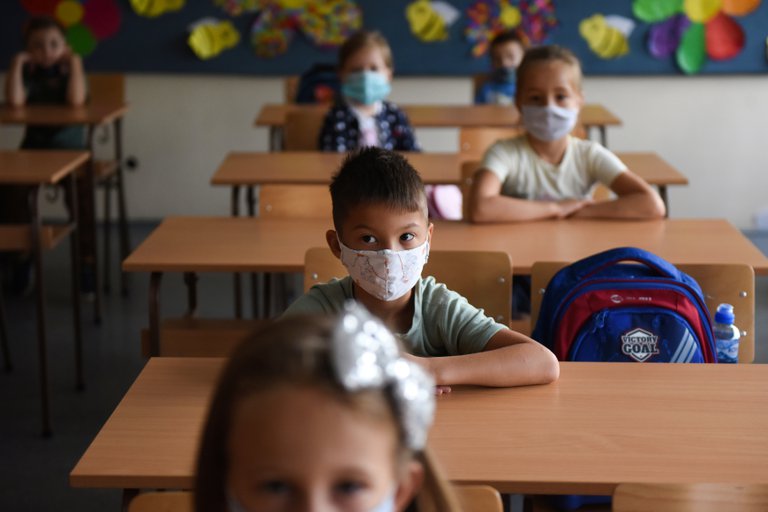 Niños dando clases con tapabocas.