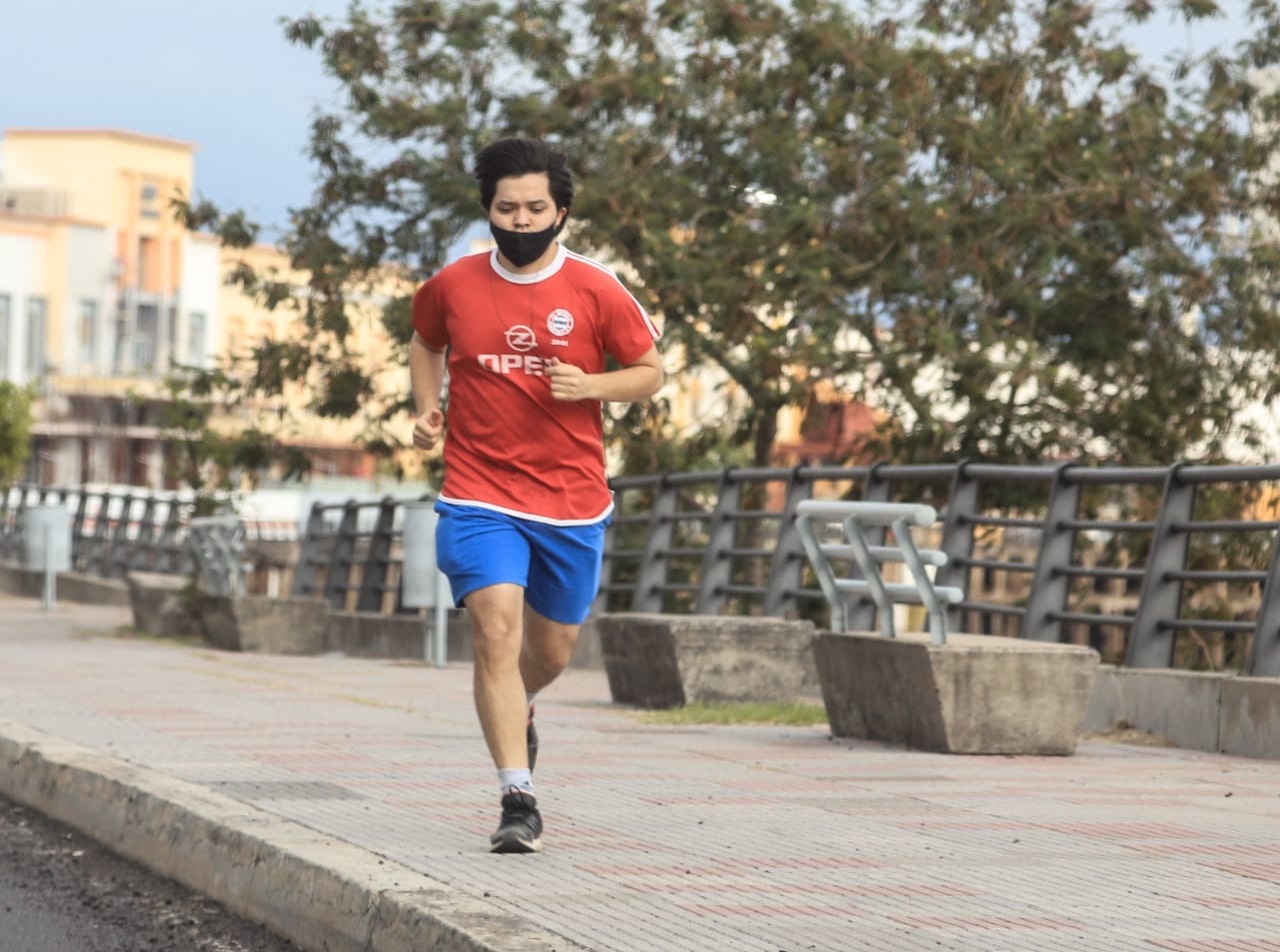 Hombre corriendo en la costanera vistiendo un tapabocas.